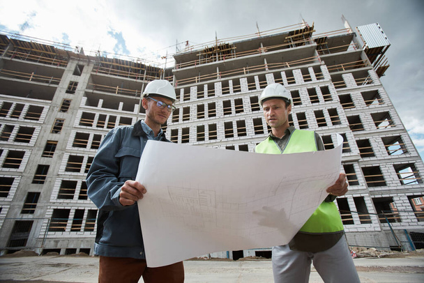Travailleurs de la construction ayant des plans d'étage - Photo, image