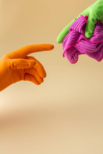 Guantes de goma multicolores que sostienen un paño de microfibra para lavar, concepto de limpieza - Foto, imagen