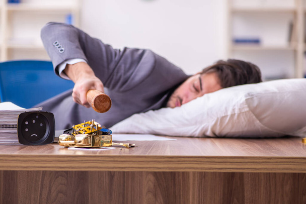Young male employee in oversleeping concept - Фото, изображение
