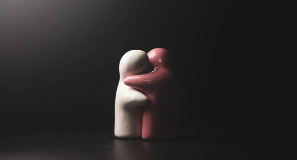 Terracotta aşıkları siyah arka planda birbirlerine sarılıyorlar. aşk kavramı ve endişesi - Fotoğraf, Görsel