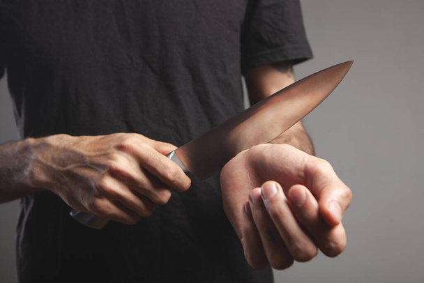un homme veut couper ses veines avec un couteau de cuisine - Photo, image