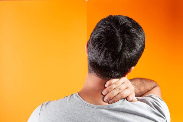 Mann hat Nackenschmerzen auf orangefarbenem Hintergrund - Foto, Bild