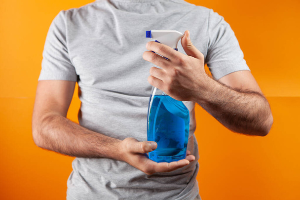 man holding detergent on orange background - Foto, afbeelding