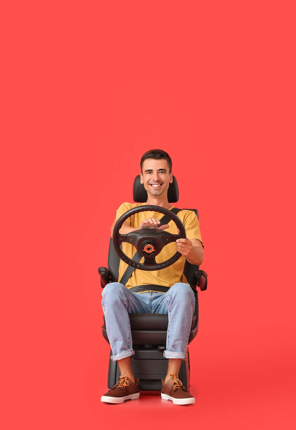 Homme dans le siège auto et avec volant sur fond de couleur - Photo, image