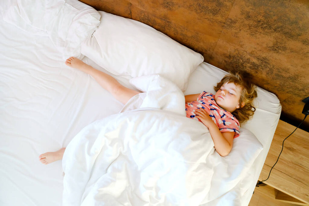 かわいい幼児の女の子はベッドで寝ています。愛らしい赤ちゃんの夢、毎日子供たちの健康的な睡眠。幼児の深い眠り。休みの子供たち. - 写真・画像