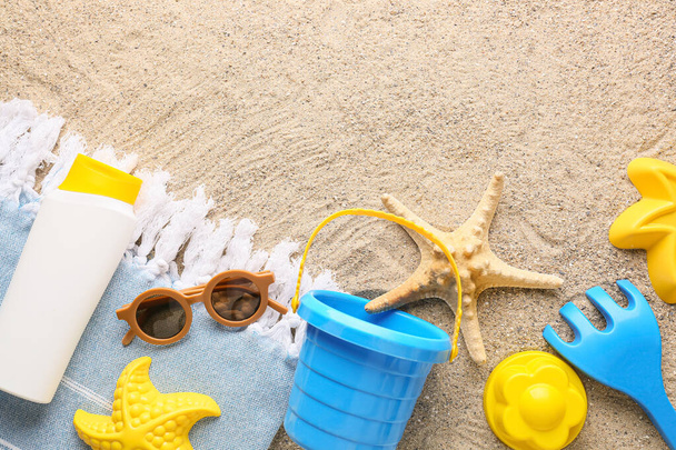 Set of beach accessories for children and bottle of sunscreen on sand - Fotoğraf, Görsel