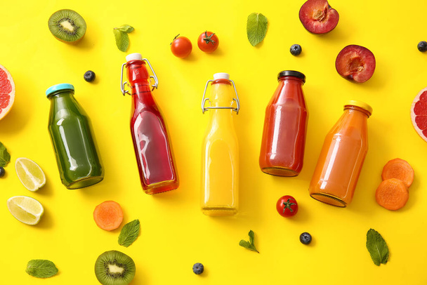 Бутылки со здоровым соком, фрукты и овощи на цветном фоне - Фото, изображение