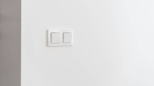 Switch light at wall, closeup to interior details. Minimalistic home design, white button for electricity energy control. Plastic on off electrical technology for house, modern equipment concept. - Foto, Imagem