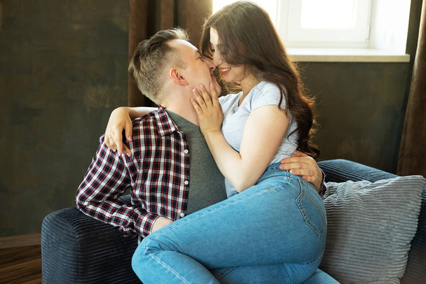 Young beautiful couple is sitting on the couch and hugging. - Valokuva, kuva