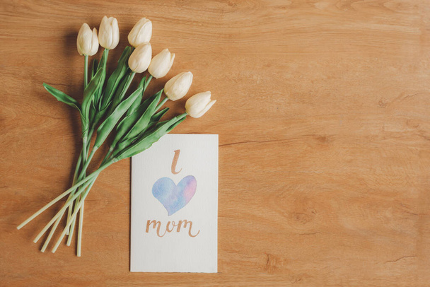 Vista superior de la tarjeta de felicitación encantadora Me encanta mamá y flores sobre fondo de madera - Foto, Imagen