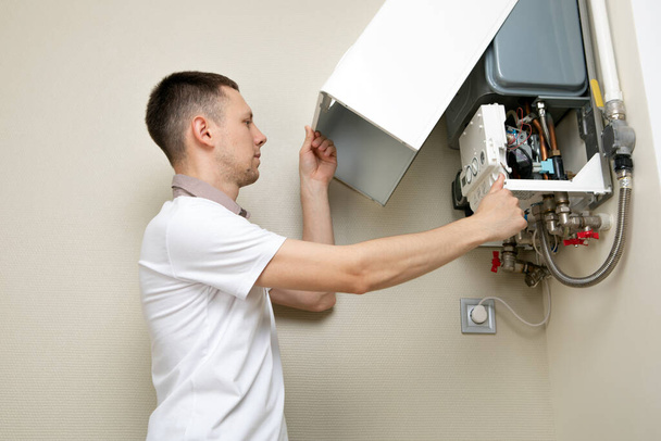 Plumber attaches Trying To Fix the Problem with the Residential Heating Equipment. Repair of a gas boiler - Фото, изображение