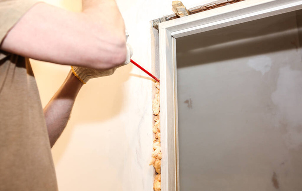 Man is installing the door with a spray foam. Repair works. Maintenance in the apartment. - Foto, imagen