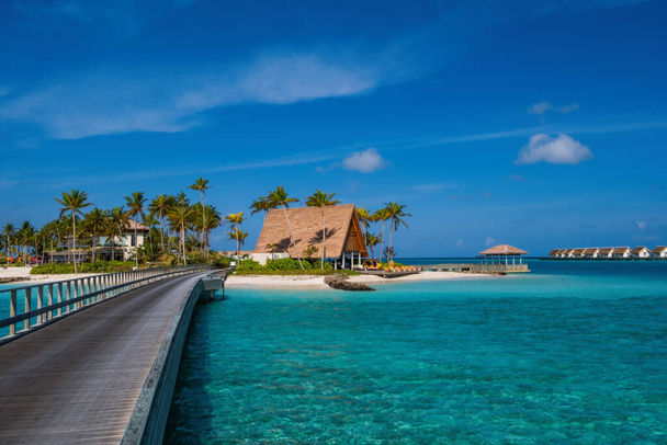 hard rock hotelgebouwen met palmen tegen de achtergrond van smaragd water. Kruispunt Malediven, juli 2021 - Foto, afbeelding