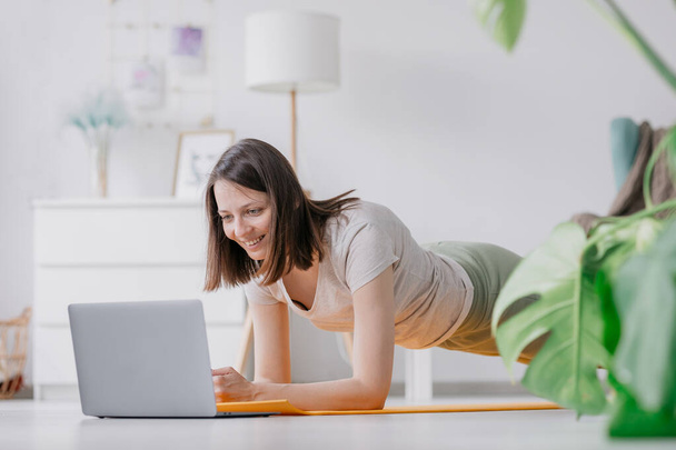 training, meditation and yoga at home, woman doing physical exercises with a laptop - Foto, afbeelding