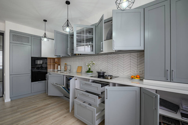 Trendy grey and white modern kitchen furniture with doors open - Fotoğraf, Görsel