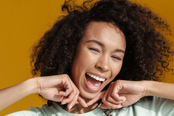 Young african woman laughing and making fun on camera isolated over brown wall - Photo, Image