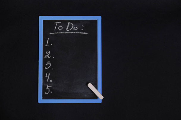 Flat lay of a chalkboard with lettering list to do, with empty copy space. Isolated on black background. Planning concepts, time management, timetable and timing. - Photo, image