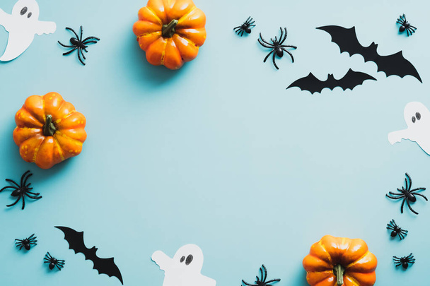 Happy halloween holiday concept. Frame of halloween decorations, bats, ghosts, pumpkins, spiders on blue background. Halloween party greeting card mockup with copy space. Flat lay, top view - Foto, Imagen