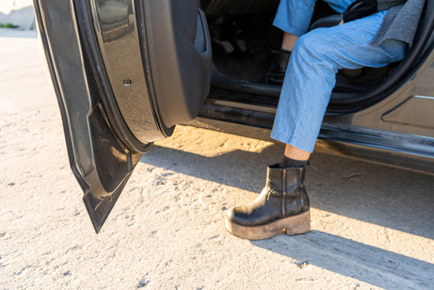 Leg of a woman with pants and boots getting out of a car. - Photo, Image