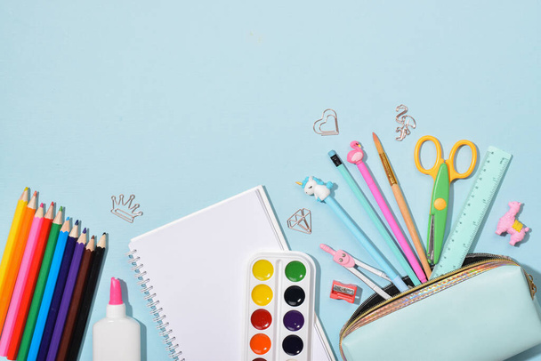 Background with stationery at the bottom on blue. Back to school. Flat layout, top view, a place to copy. - Foto, afbeelding