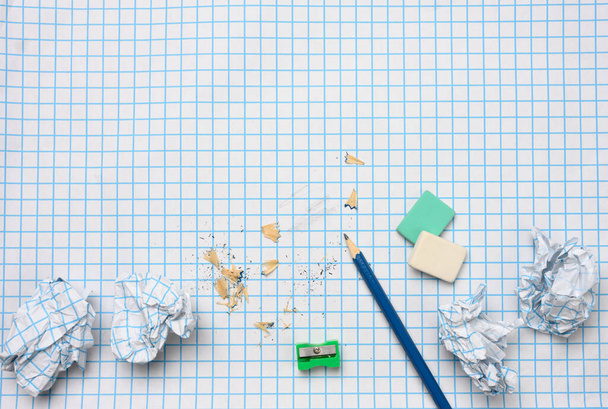 boules de papier froissées et un crayon en bois aiguisé avec des copeaux sur une feuille de papier à carreaux - Photo, image