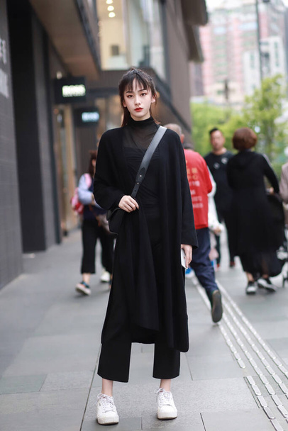 young asian woman in a black dress and a backpack walking on the street - Foto, Imagem