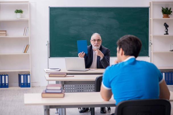 Old male teacher and young male student in front of blackboard - Foto, Bild