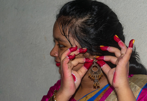 インド人女性が彼女のイヤリングを見せた。黄金のイヤリングと指に焦点を当てます。結婚式の日や祭りの化粧の概念. - 写真・画像