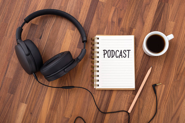 Podcast concept with headphones and coffee cup on wooden desk, top view - Foto, Bild