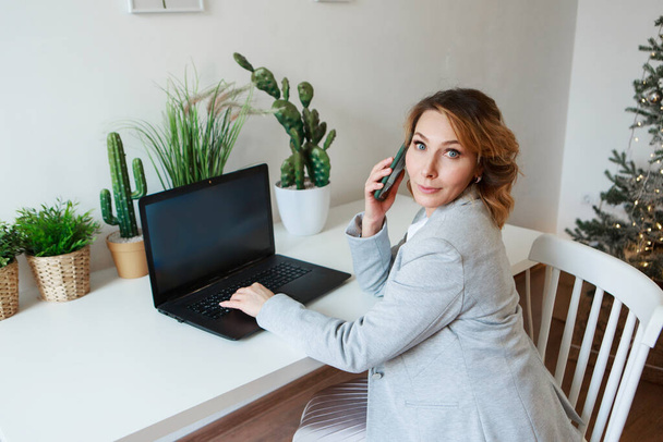 office concept, business plan, fashion-businesswoman in black and yellow suit talking on the phone and working on a laptop. Beautiful woman sitting on chair on white background - Φωτογραφία, εικόνα