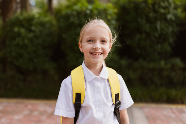 Schoolgirl back to school after summer vacations. Child in uniform smiling early morning outdoor.  - Foto, Imagen