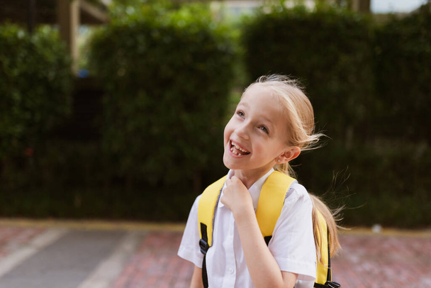 Schoolgirl back to school after summer vacations. Child in uniform smiling early morning outdoor.  - Foto, Bild