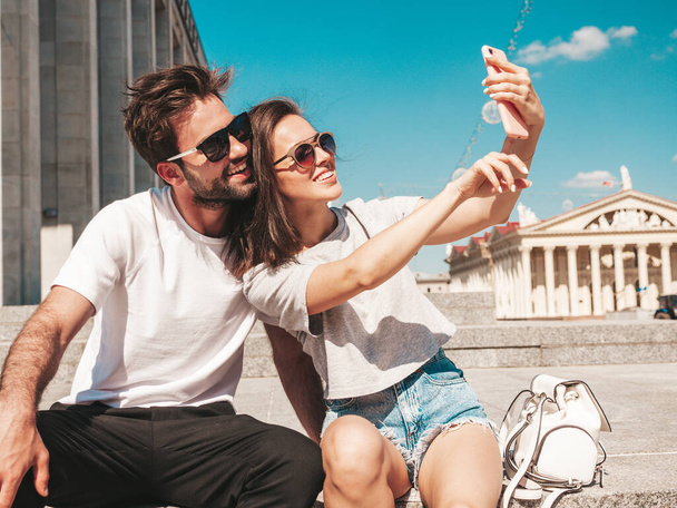 Portrait of smiling beautiful woman and her handsome boyfriend. Woman in casual summer clothes. Happy cheerful family. Female having fun. Couple posing in the street in sunglasses.Taking selfie photos - Zdjęcie, obraz