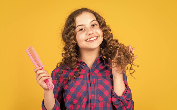 Hairstyle for party. Hairdresser supplies. Little child curly hair. Fashion and beauty. Small girl hairdresser salon. Brushing long hair. Enjoying shiny curls. Balm oil conditioner for styling - Foto, Imagen