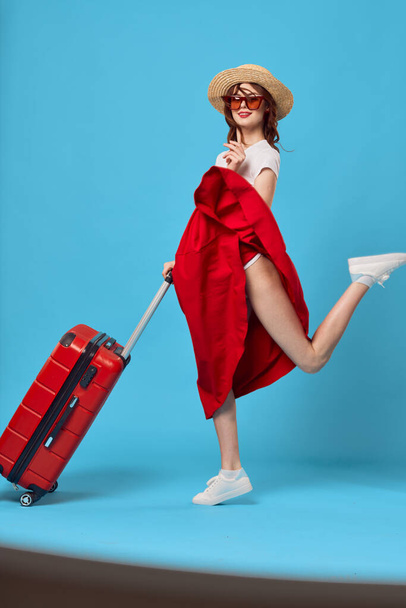pretty woman with red suitcase sitting on luggage vacation blue background - Photo, Image