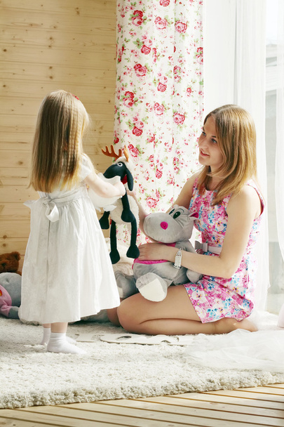 Pretty blonde little girl and her mother play with soft toys nea - Foto, Bild