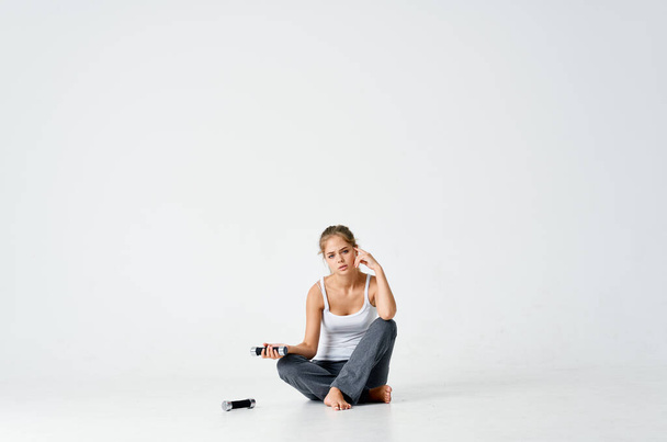 woman in sports uniform sitting on the floor dumbbells exercise workout gym - Foto, Imagen