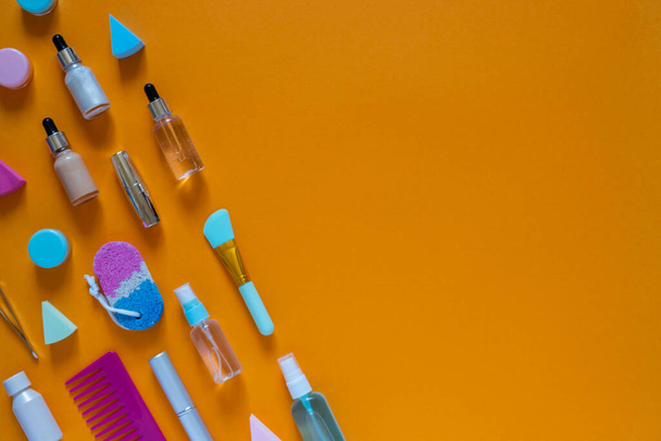 Flat composition with cosmetic products on an orange background. Multicolored sponges. Womens self-care. Top view image - Photo, Image