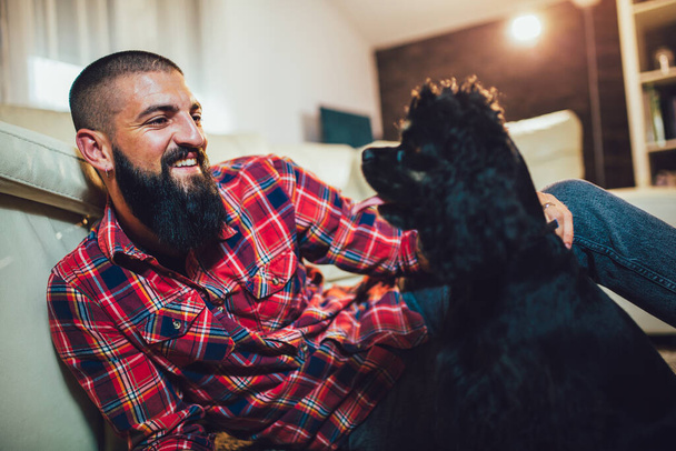 Best Friend Concept. Handsome man with cute dog at home. - Fotó, kép
