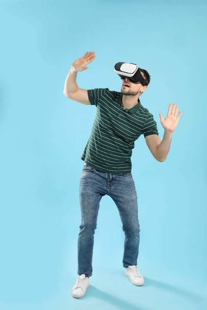 Man using virtual reality headset on light blue background - Foto, Imagen