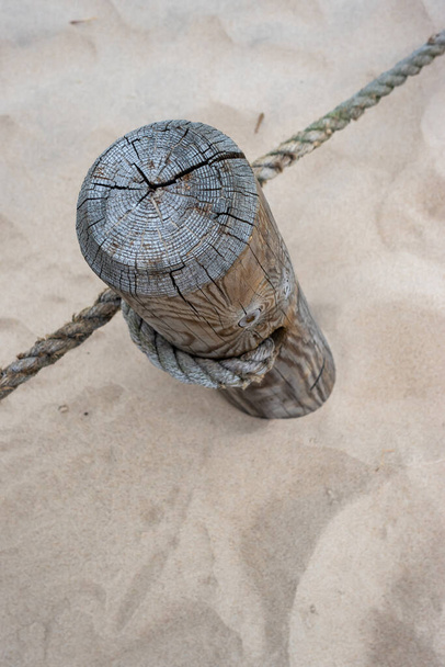 Een houten paal met uitgerekte touwen die het wandelpad scheidt van het beschermde gebied. Foto genomen in goede lichtomstandigheden op een bewolkte dag - Foto, afbeelding
