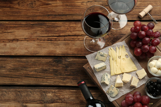 Tasty red wine and snacks on wooden table, flat lay. Space for text - Foto, Bild
