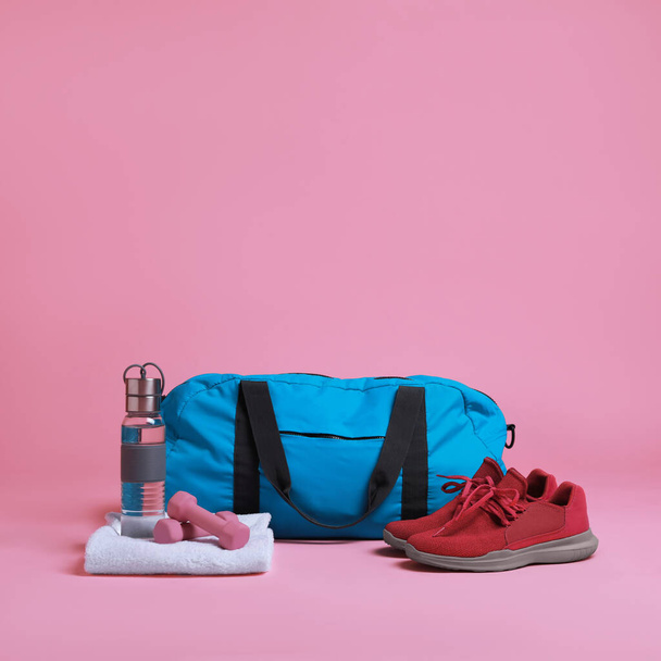 Blue gym bag and sports accessories on pink background - Foto, afbeelding