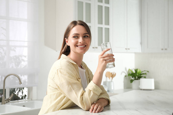 Mujer con vaso de agua del grifo en la cocina - Foto, Imagen