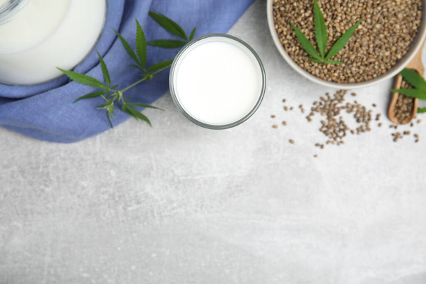 Hemp milk and seeds with fresh leaves on light grey table, flat lay. Space for text - Foto, Imagem