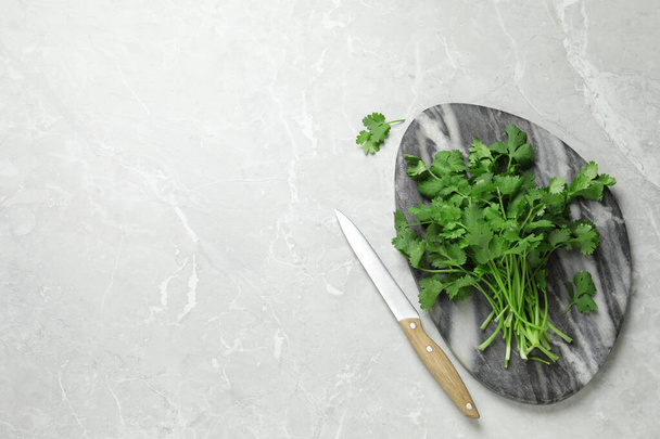 Bunch of fresh aromatic cilantro and knife on light marble table, flat lay. Space for text - Фото, зображення