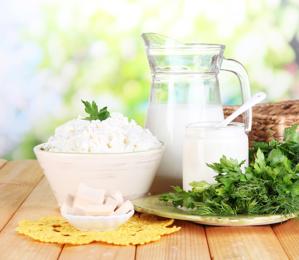 Fresh dairy products with greens on wooden table on natural background - Foto, immagini
