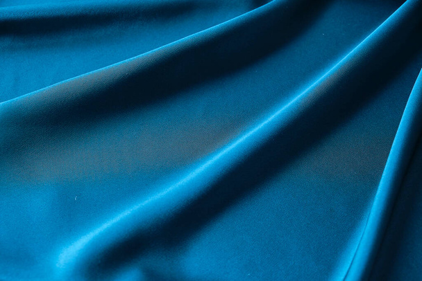 Blue silk drapery and upholstery fabric from the courtyard. Blue satin, silky fabric, wave, draperies. Beautiful textile backdrop. Close-up. Top view - Foto, imagen