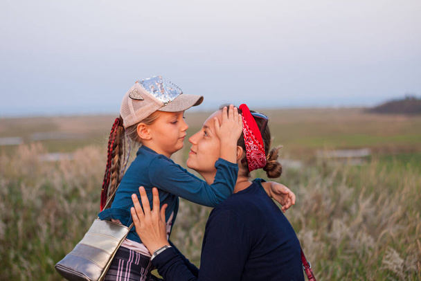 Mother and daughter hugging on nature landscape. Mom with child walking in the evening outdoor. Love, care, friendship, stress, relationship concept. - Photo, Image