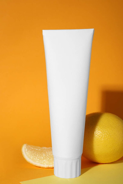 Blank tube of toothpaste and fresh lemon on color background - Фото, зображення